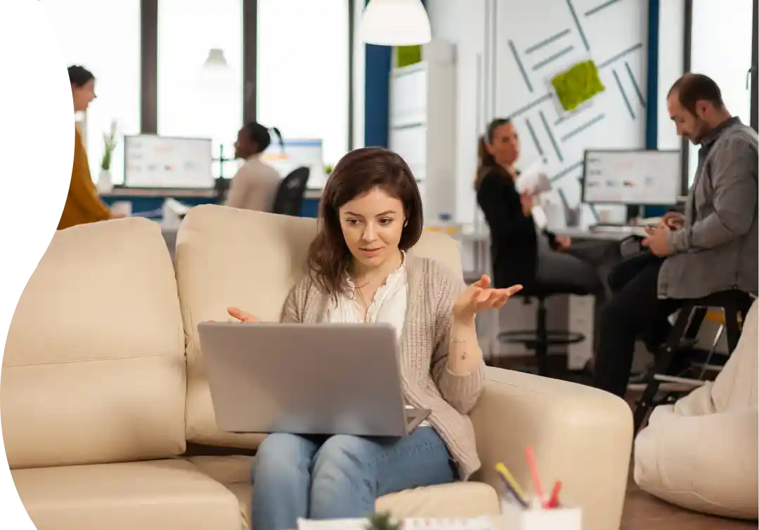 A young woman enjoys Ultranet's high-speed internet on her laptop, seamlessly working in a busy office with reliable, stable connectivity